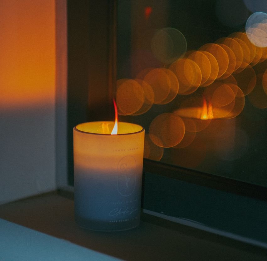 A candle placed by the window with reflections of light