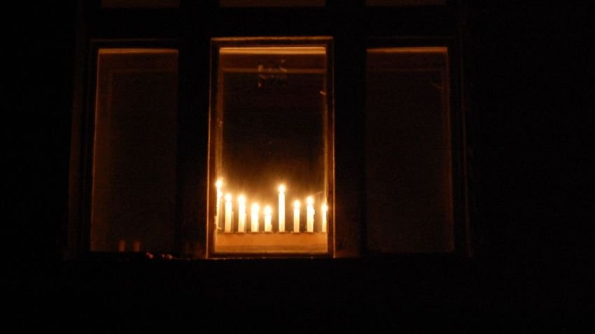 Hanukkah Menorah candles put in a window viewed from outside the window